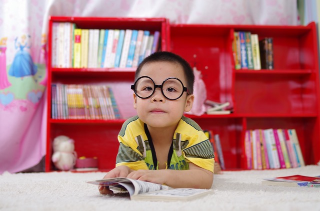 Asian boy with large glasses reading a book